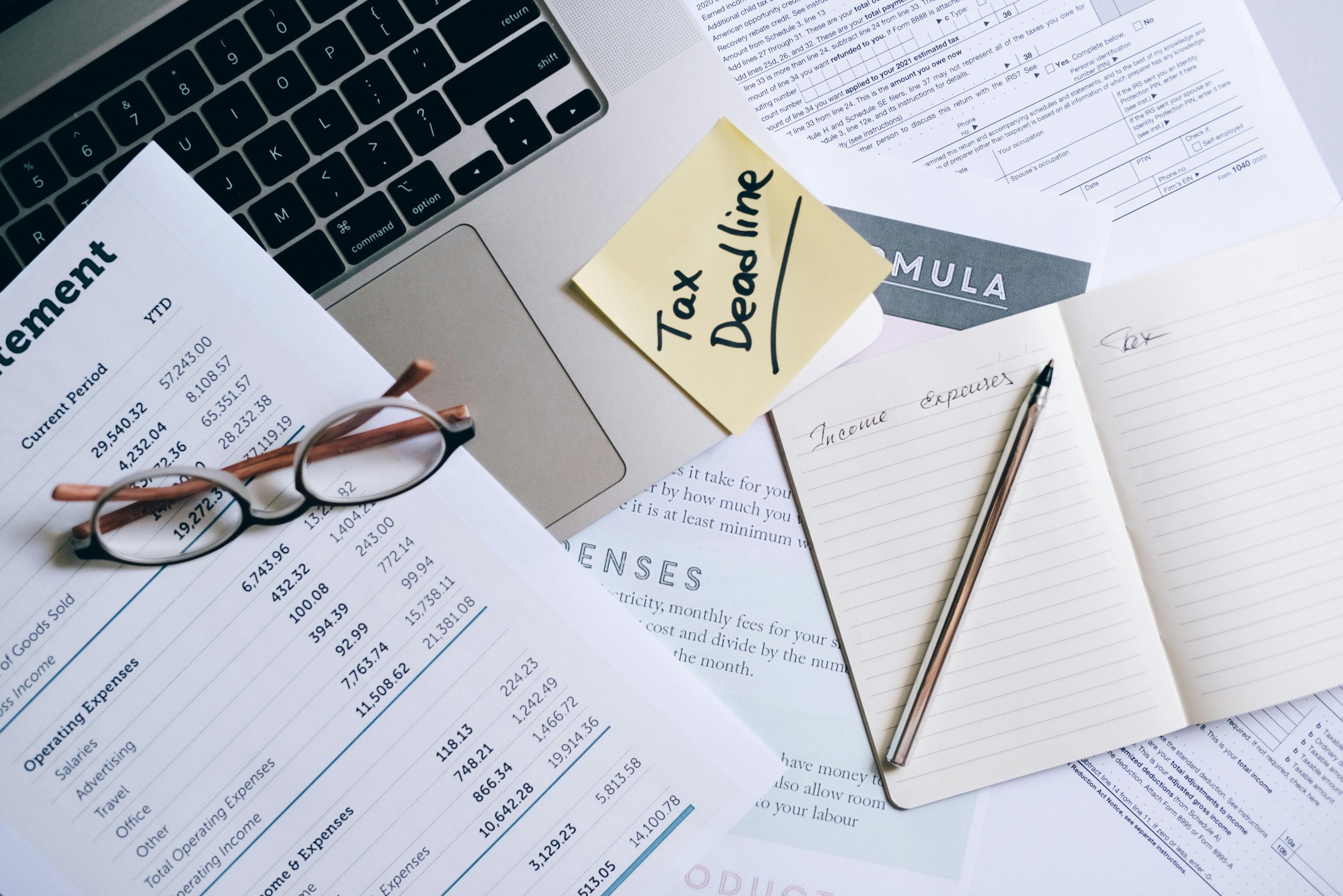 financial documents and a laptop with a 'Tax Deadline' sticky note
