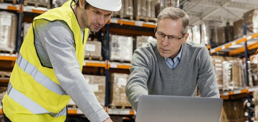 warehouse employee and manager looking at a laptop screen