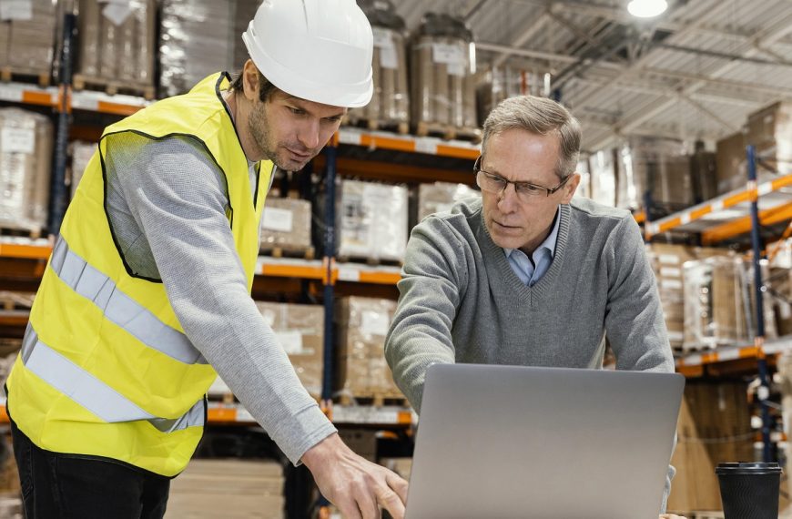 warehouse employee and manager looking at a laptop screen