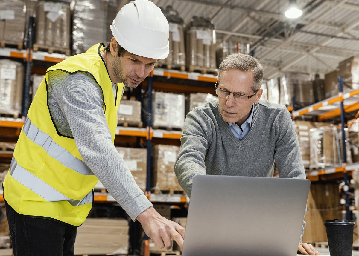 warehouse employee and manager looking at a laptop screen